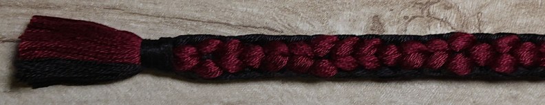 an uneven black and red braid with a tassel on one end