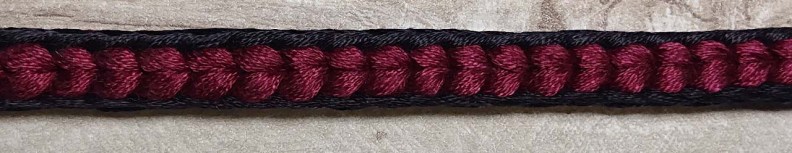 A black and red braid that looks like a hair plait with black borders. 